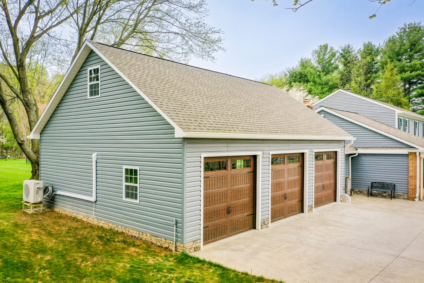 exterior of blue 3-car garage for sale in ny by green grass