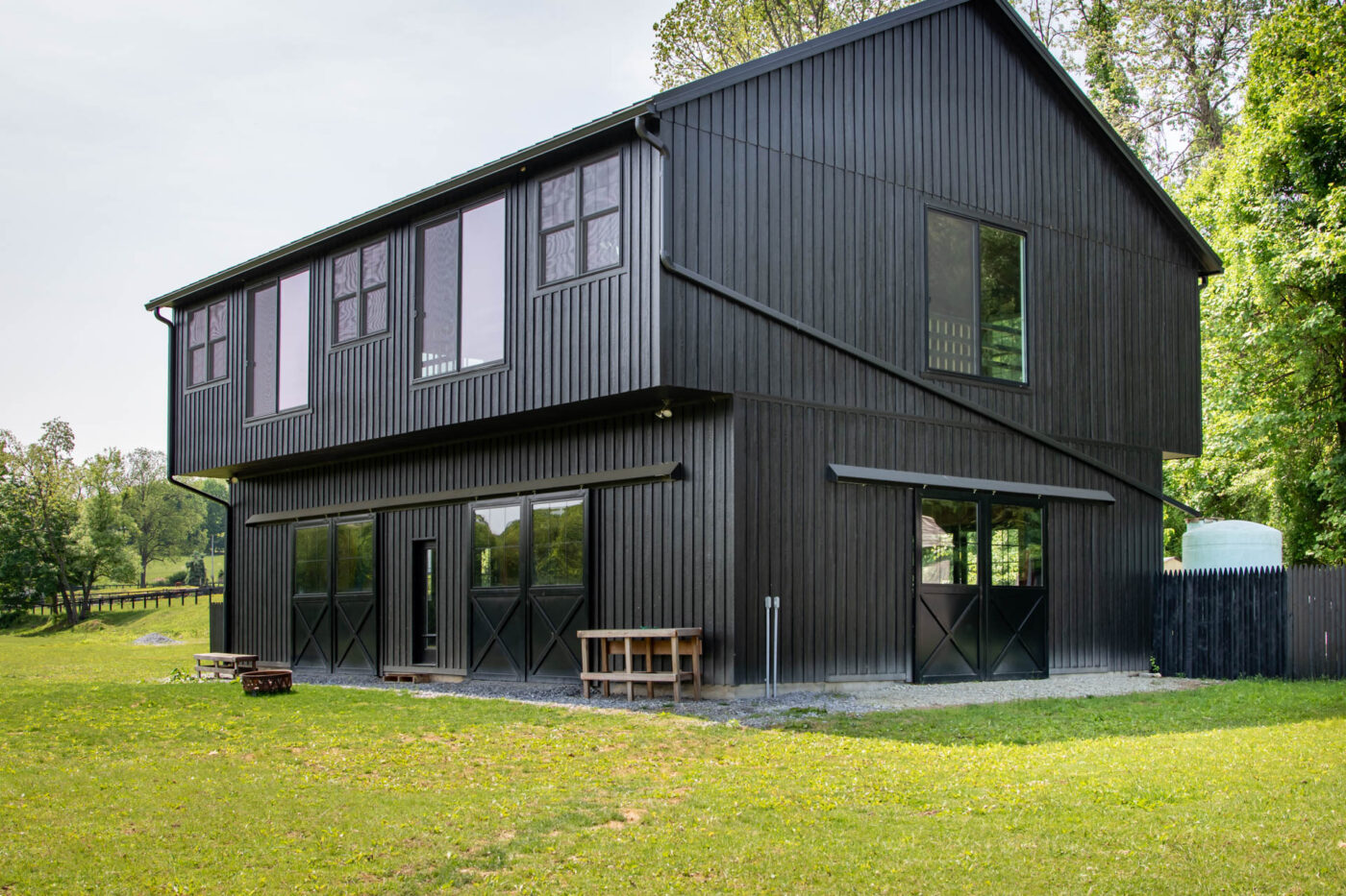 black 2-car garage with larger second story, metal roof, and sliding garage doors