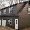 the exterior of an dark grey workshop 2-Car garage in lyme, ct with white windows and doors and black shingles