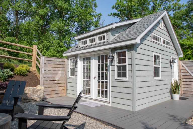 A Modern gray shed with gray vinyl shaker siding. white doors and window highlight the features of this finished shed.