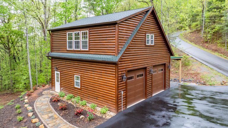 aerial side of a 28x40 legacy 2-story workshop 2-car garage with custom matched dark oak pine log tongue and groove siding, and Hunter green GAF Timberline HDZ shingles on the roof