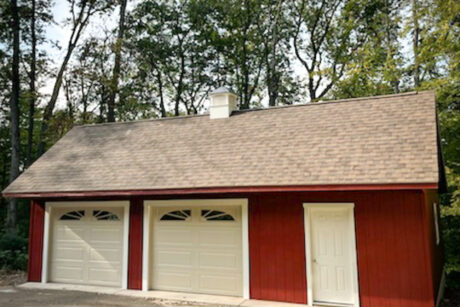the exterior of a barn red single-story saltbox 2-car garage in Pottstown, PA with white trim and Dual Brown shingles