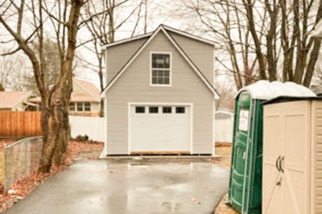 the exterior of a 2-Story workshop single-car garage in South Portland, ME with slate gray vinyl siding, white trim, and dual black shingles