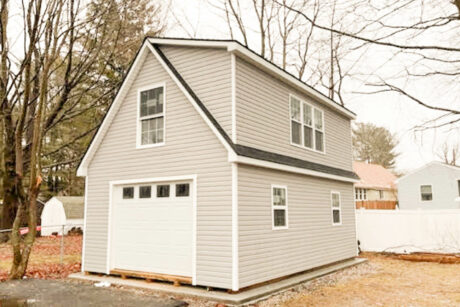 the exterior of a 2-Story workshop single-car garage in South Portland, ME with slate gray vinyl siding, white trim, and dual black shingles
