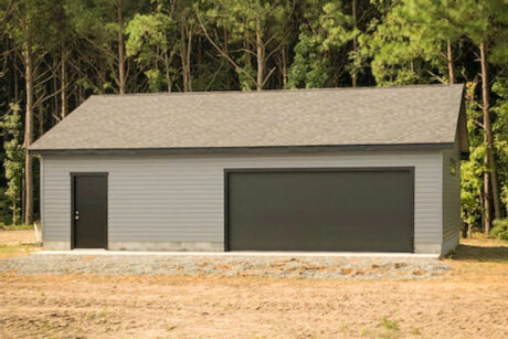the exterior of a gray single-story workshop 2-car garage in Kinsale, VA with black trim, custom siding, and black garage doors