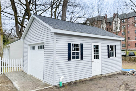 a gray prefab one-car garage with black shutters and loft