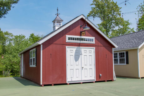 red premier workshop shed with white trim, transom window, cupola, and black shutters
