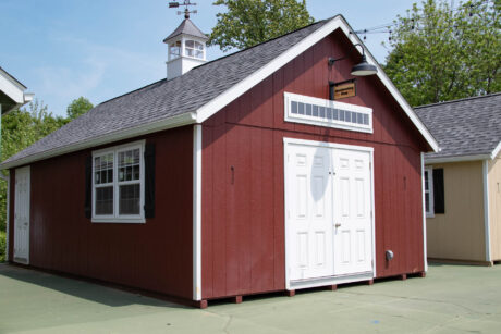 red premier workshop shed with white trim, transom window, cupola, and black shutters