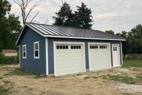 A blue 2-car prefab workshop garage with black standing seam metal roof