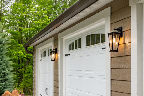 close up of carriage style white garage doors with lamps lit up beside them