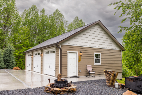 view of the side of a tan and white trimmed 28x38 with side door and fire pit