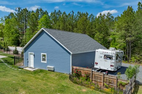 Aerial side view of a early american blue T111 smart sided 28x40 single story workshop 3-car garage with Charcoal gray Architectural Shingles and white trim