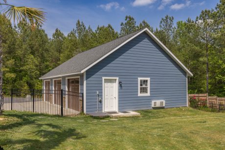 Side view of a 28x40 single story workshop 3-car garage, with early american blue smart siding, white trim and side door, and charcoal gray Architectural shingled roof that includes a 12-inch overhang