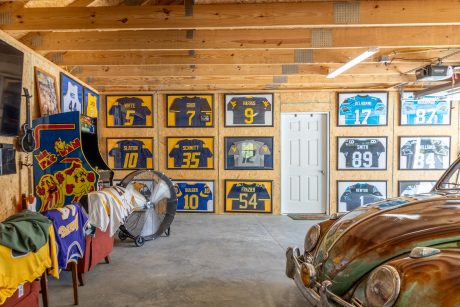 multiple collegiate and NFL jerseys hang displayed on the dividing wall in a partially enclosed 24x80 single story workshop 3-car garage