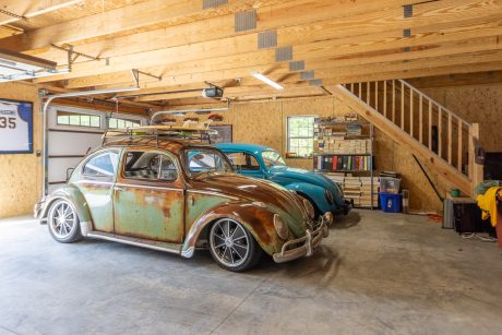 Two restored antique 1970's Volkswagen bugs inside a partially enclosed 28x40 single story workshop 3-car garage including stairs to a storage space above the garage