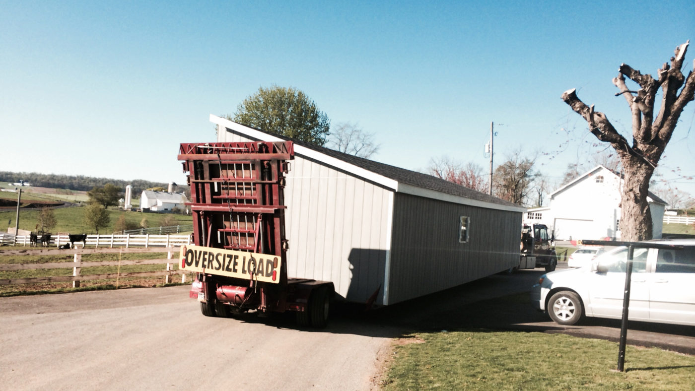 exterior of big delivery truck and half of double wide shed