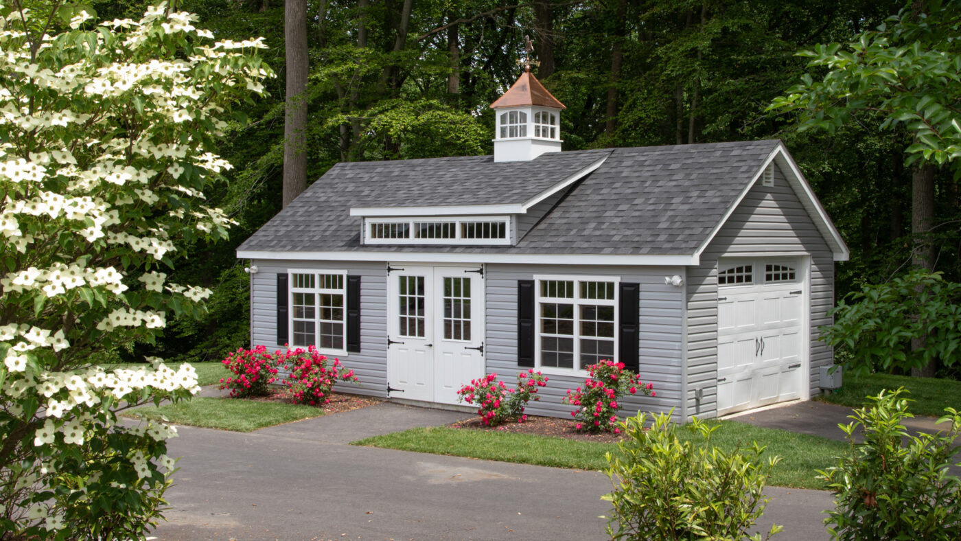 gray garage with dormer and cupola featuring white double doors and white carriage garage doors